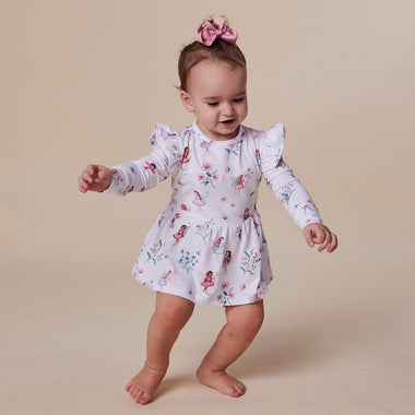 Baby girl in a fairy dress standing on a beige background