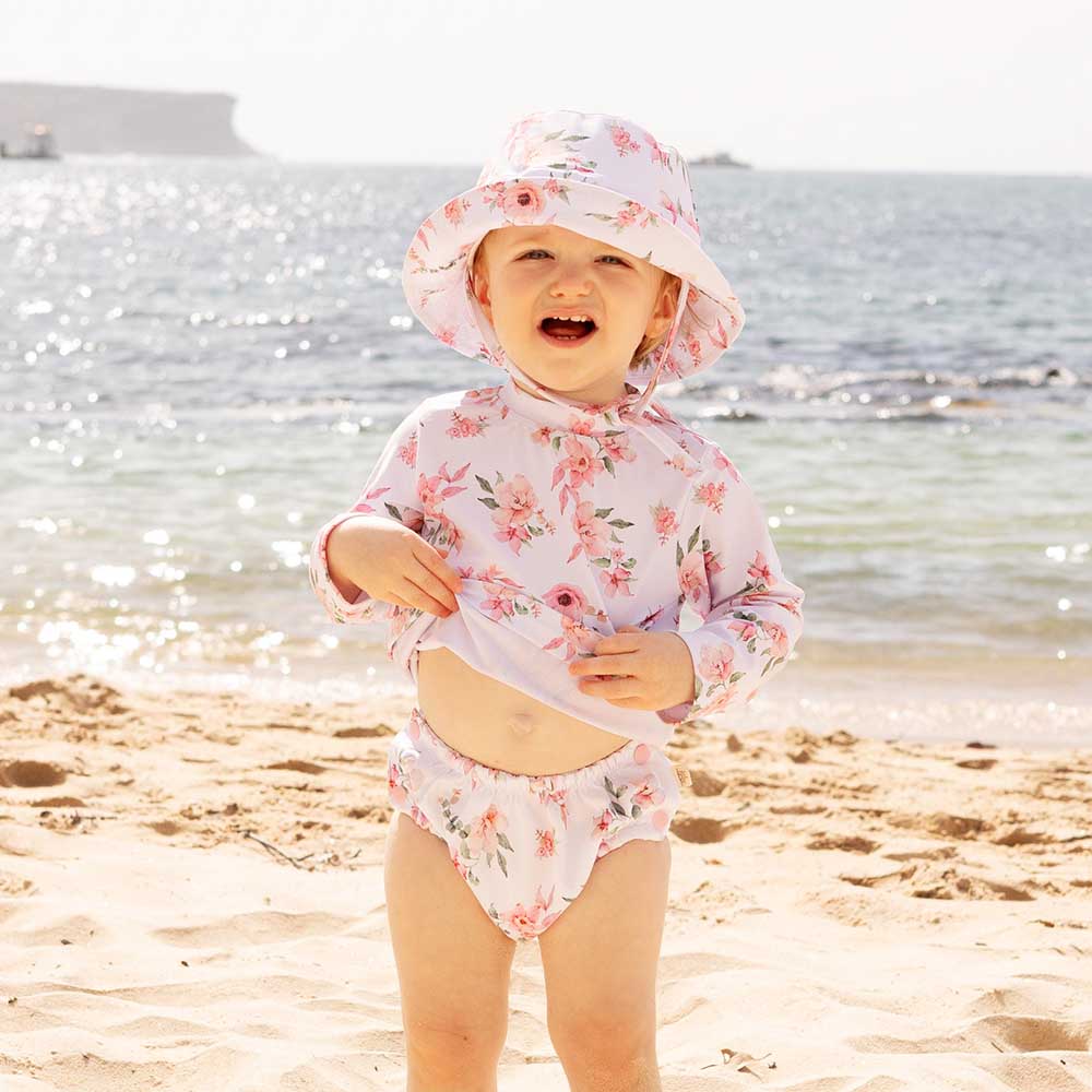 Little Girl In Swimming Hat And Pink Rash Top Playing In Wet Sand